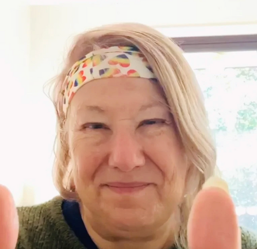 Person with a colorful headband giving a thumbs-up gesture.